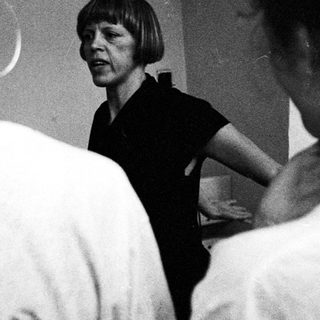 Group of people interact with a woman in a room.