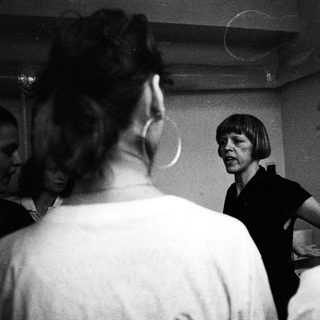 Group of people interact with a woman in a room.