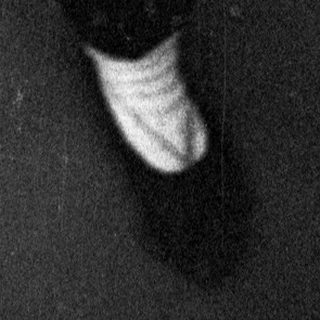 Person seated on the floor, looking upward in a dark space.