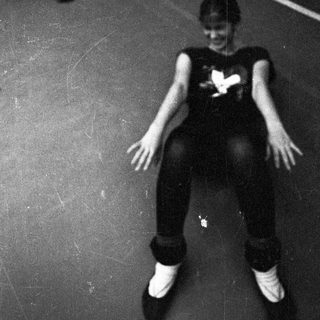 Person seated on the floor, looking upward in a dark space.