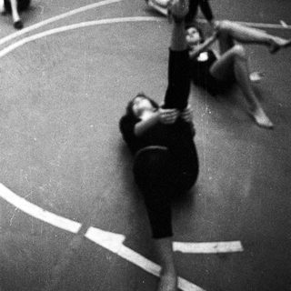 Ballet dancers practice in a studio, one lifted.