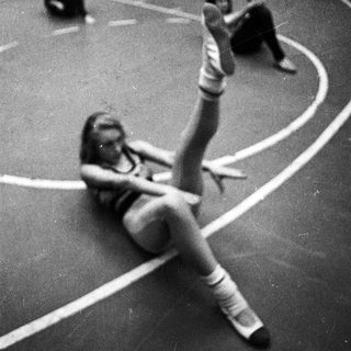 Here's a brief summary of the image: Gymnast practicing a floor exercise in a black and white photo.