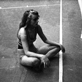 Here's a brief summary of the image: Four young women in athletic wear in a gym.
