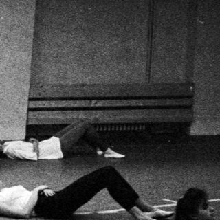 Ballet class with a teacher and students on the floor.