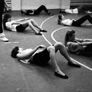Ballet class with a teacher and students on the floor.