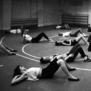 Black and white photo of people stretching on a basketball court.