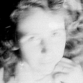 Here's a brief summary: Faded, blurred portrait of a child near a window.