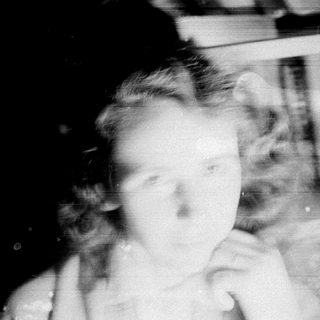 Here's a brief summary: Faded, blurred portrait of a child near a window.