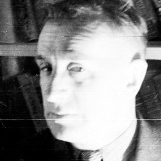 Man stands near a bookshelf in a black and white photo.