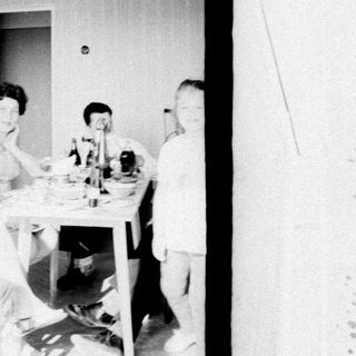 Here's a brief summary of the image: People seated at a table, and a person walking a path.