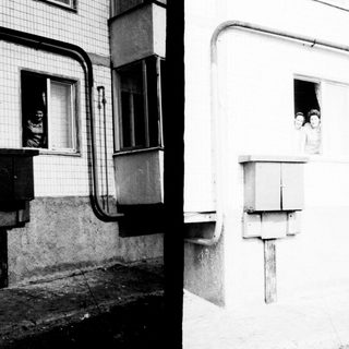Here's a brief summary of what the image shows: People peering out of a window, attached to a building.
