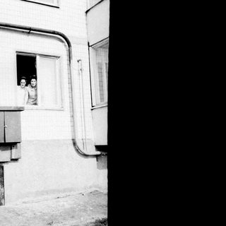 Two young girls peering out of a window.