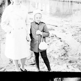 Woman and child standing near a body of water.