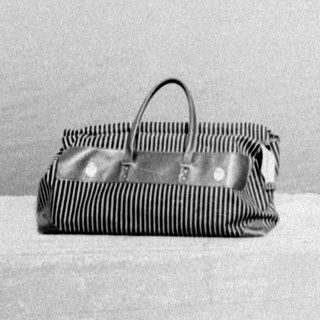 Woman stands with child, bag nearby on snowy ground.