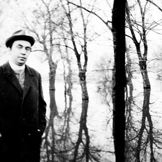 Man in coat stands near a body of water.