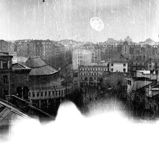 Vintage photograph shows a cityscape with buildings and a sky.