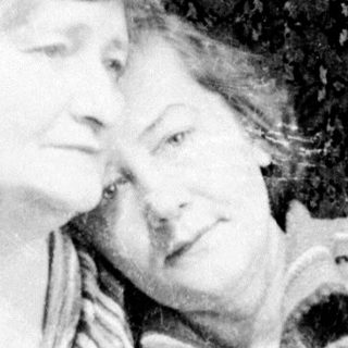 Two women in patterned robes are seated together.