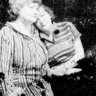 Two women in patterned robes are seated together.