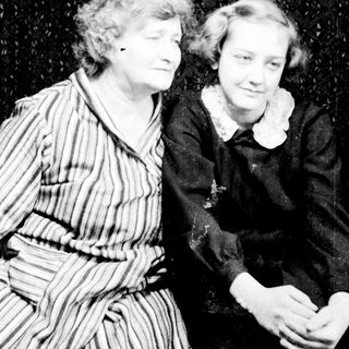 Two women pose for a vintage portrait, smiling.