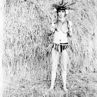 Here's a brief summary of the image: Man in traditional attire stands in tall grass.
