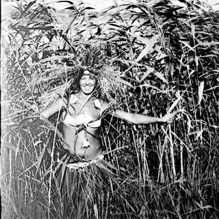 Woman stands partially obscured within tall grass.