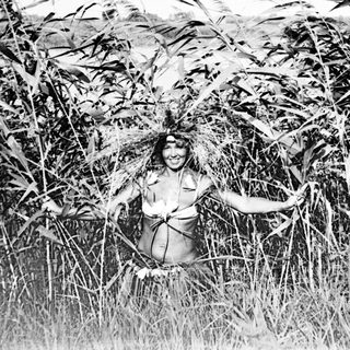 Person stands in tall grass, partially obscured by foliage.