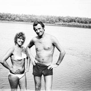 Couple in swimwear standing near a body of water.