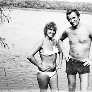 Couple in swimwear standing near a body of water.