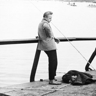 Men fishing on a pier overlooking water and boats.