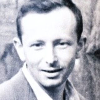 Man in suit stands near trees, captured in a vintage photograph.