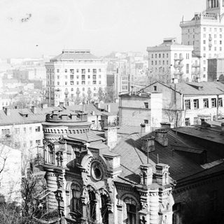 Here's a brief summary of the image: Historic cityscape with buildings and rooftops in a vintage photo.