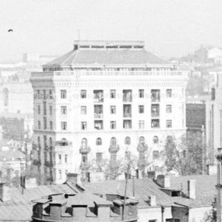 Here's a brief summary of the image: Historic cityscape with buildings and rooftops in a vintage photo.