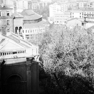 Black and white image of a cityscape with buildings and trees.