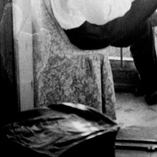 Man seated on balcony, appears to be reading or writing.