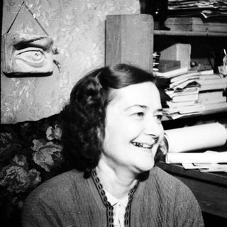 Smiling woman seated near a desk and bookshelves.