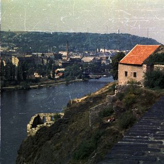 Building overlooks a river, with industrial landscape in the background.
