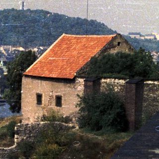 Building overlooks a river, with industrial landscape in the background.