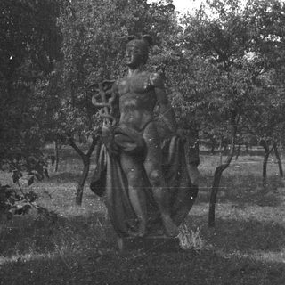 Statue of a man with a snake in a park.