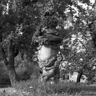 Ornate monument surrounded by flowers and trees in a park.