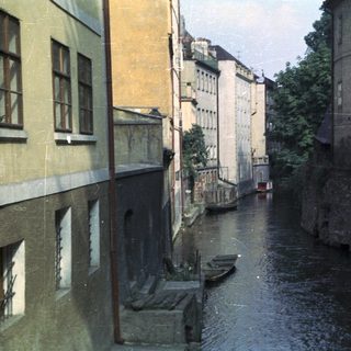 Buildings line a canal with boats in a European city.