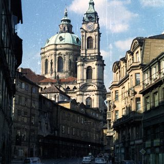Street view of baroque church with cars in Prague.