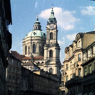 Street view of baroque church with cars in Prague.