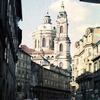 Here's a brief summary of the image: Church facade dominates street lined with old buildings.