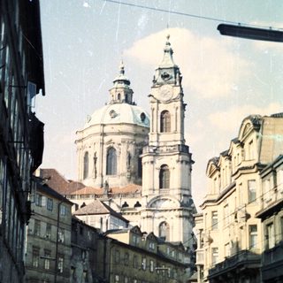 Here's a brief summary of the image: Church facade dominates street lined with old buildings.