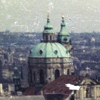Prague cityscape featuring a church and rooftops.