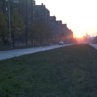 Long, empty street with buildings at sunset.