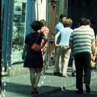 Street view of a tall building and people walking.