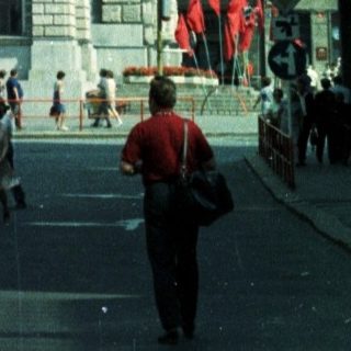 Street view of a tall building and people walking.