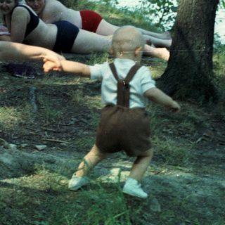 Woman reaches for a toddler near a body of water.