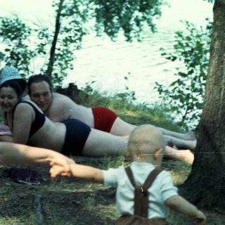 Woman reaches for a toddler near a body of water.